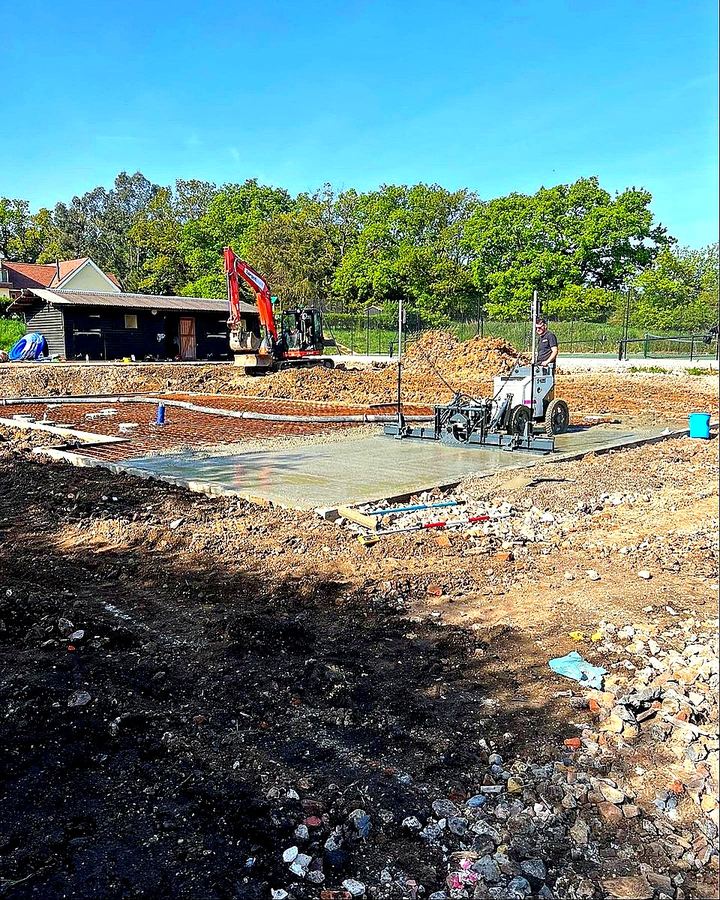 Laser-guided power float screeding of precision concrete slab with mini digger on site